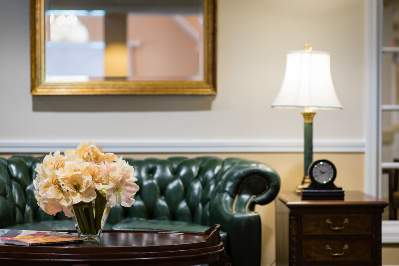 Off-white floral arrangement on a coffee table in front of a green leather sofa