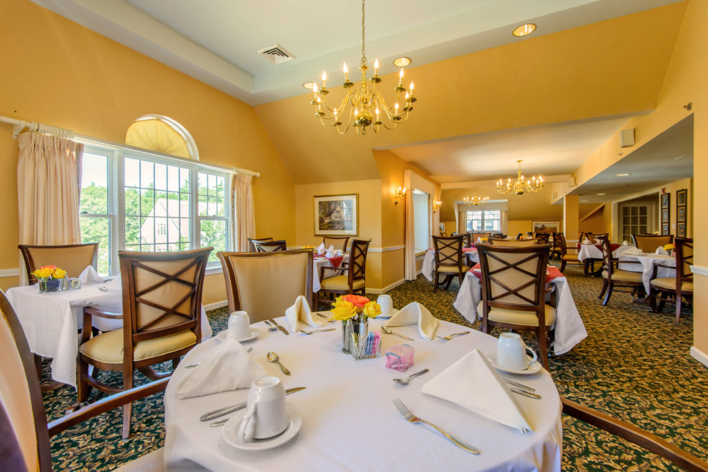 Yellow dining room with tables set for dinner