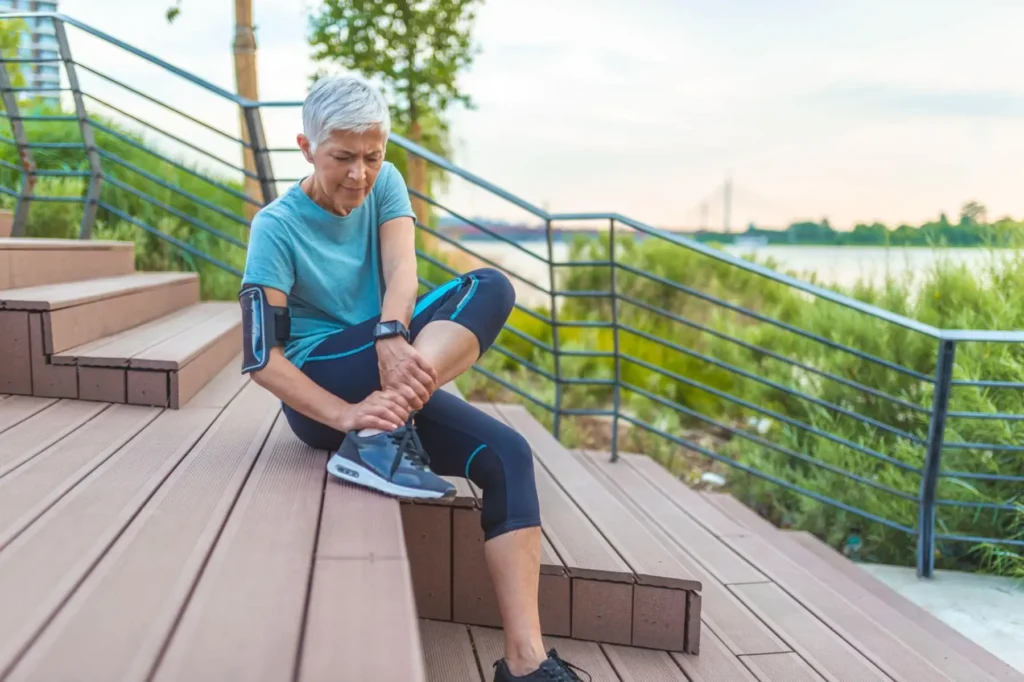a senior woman gingerly rubbing her ankle after her morning jog