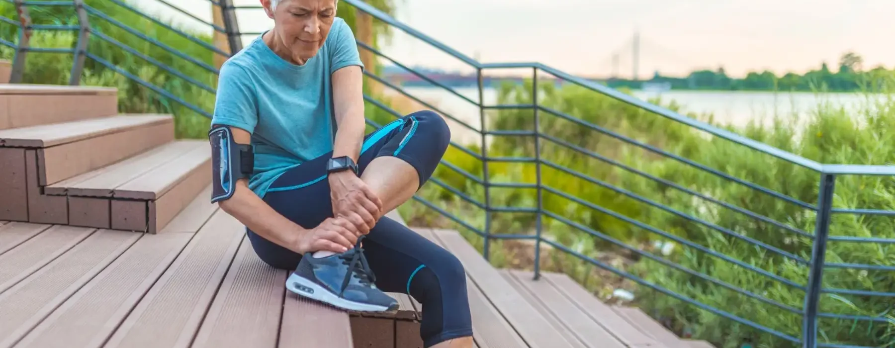 a senior woman gingerly rubbing her ankle after her morning jog