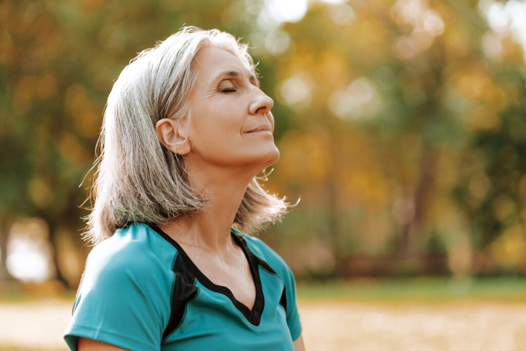 Senior woman in nature to manage anxiety and support wellness at the Village at Duxbury in MA.