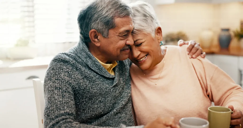 Senior couple embraces on couch after discussing the average age of assisted living.