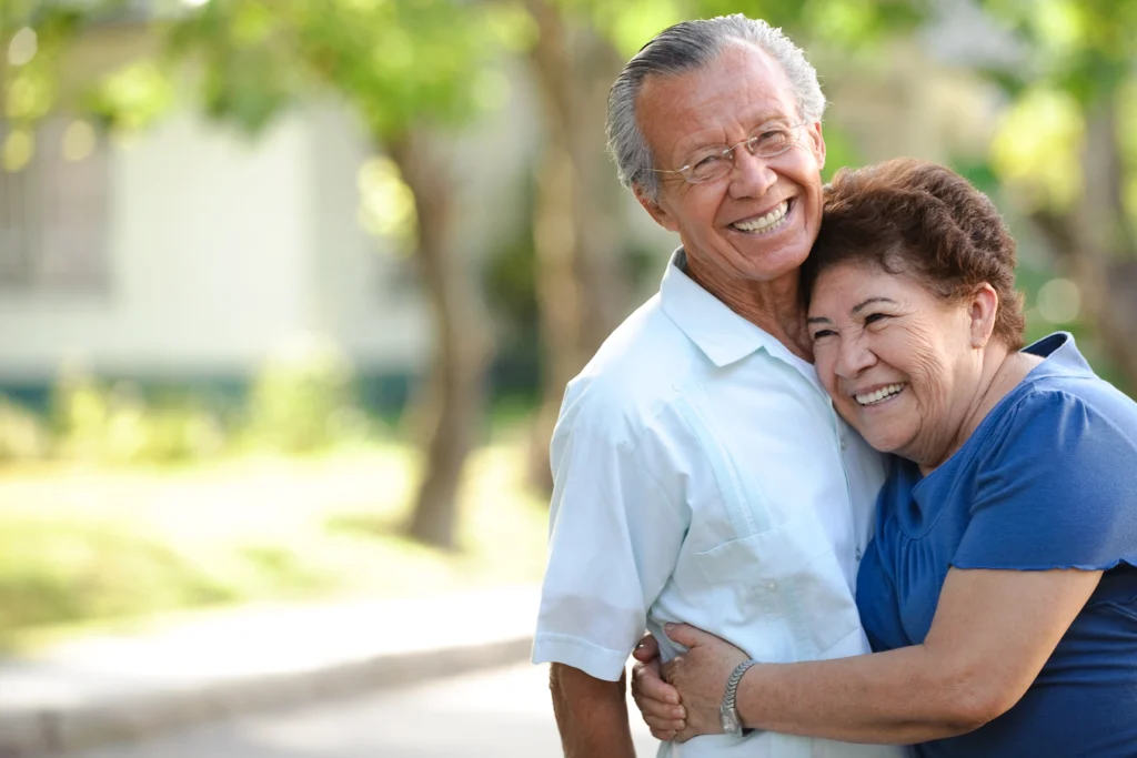 A senior couple hugging outside of The Village at Duxbury in MA, while discussing what is independent living for seniors.