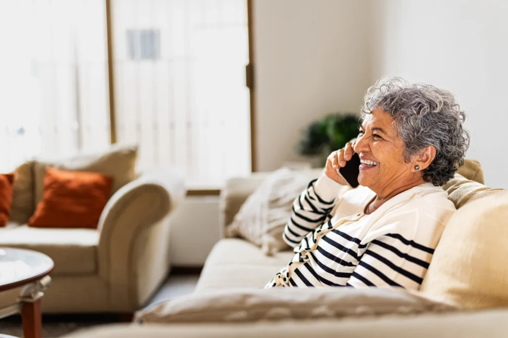 Is Assisted Living Tax Deductible? A Simple Guide for Seniors and Families 5 A senior woman talking on phone sitting on couch asking: is assisted living tax deductible in Duxbury, MA?