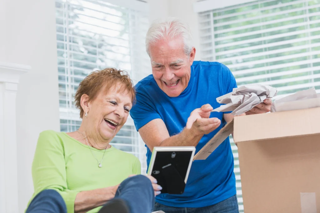 Downsizing for Retirement In Massachusetts: Simplify Your Home, Maximize Your Life 5 A senior couple downsizing for retirement in Massachusetts as they look at pictures and prepare to move to The Village at Duxbury.