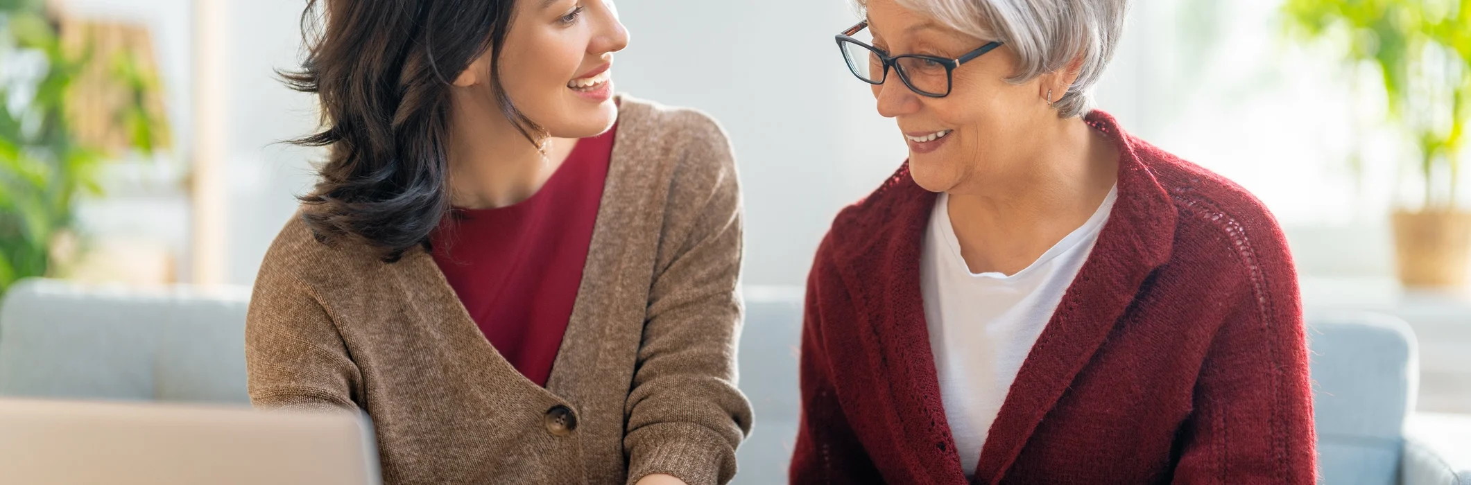 Adult daughter and senior woman taking notes, looking at laptop, and talking about moving to assisted living in Duxbury, Massachusetts.
